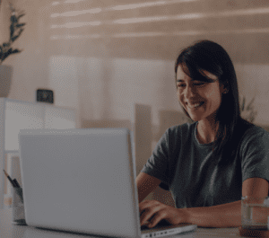 Mujer joven sonriente trabajando frente a su computador.