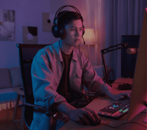 young man with headphones sitting in front of a computer.