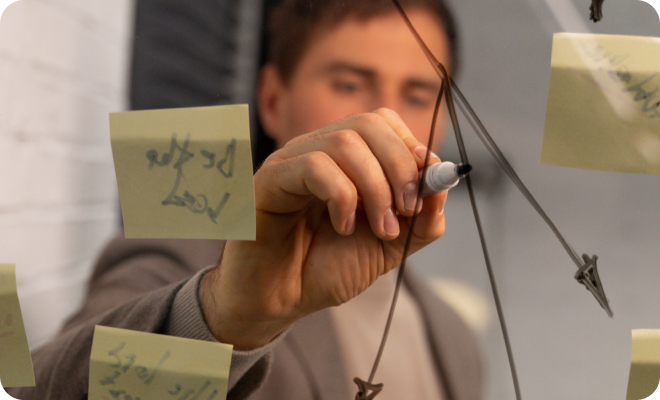 Jóven escribiendo sobre una pizarra transparente.